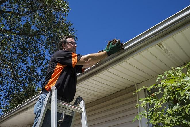 a roofer repairing a damaged gutter on a house in Coral Springs, FL